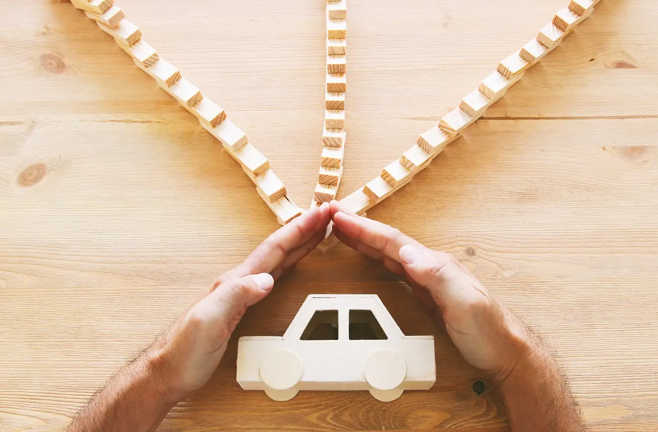 Hand sheltering car from falling dominoes